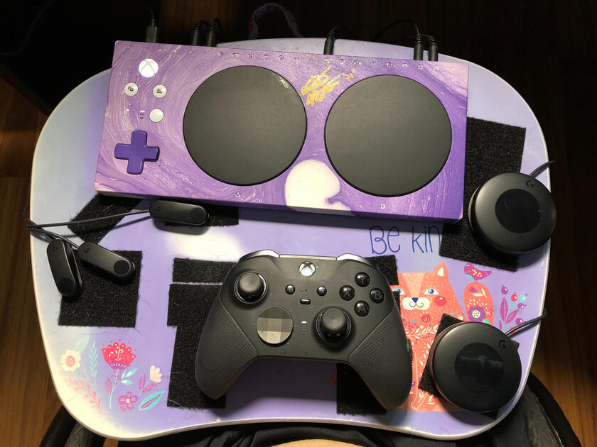 xbox adaptive controller set up with a purple XAC unit on top and logitech buttons arranged around controller with a classic xbox controller on lap-pad